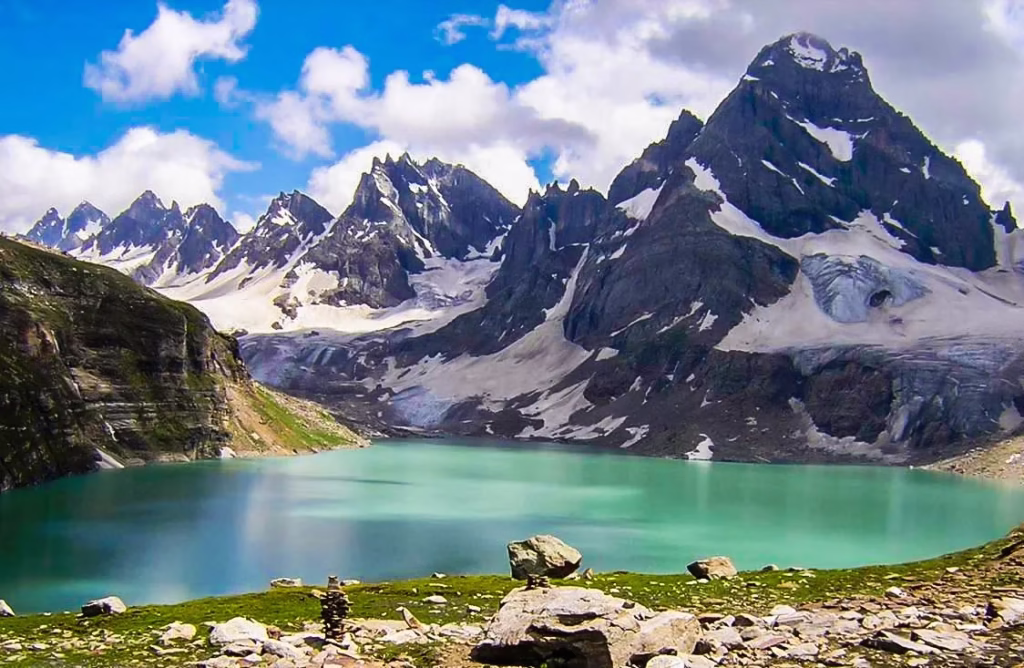 Photo of Chitta Katha Lake showing the white quartzite rocks, clear water, and snow peaks behind.