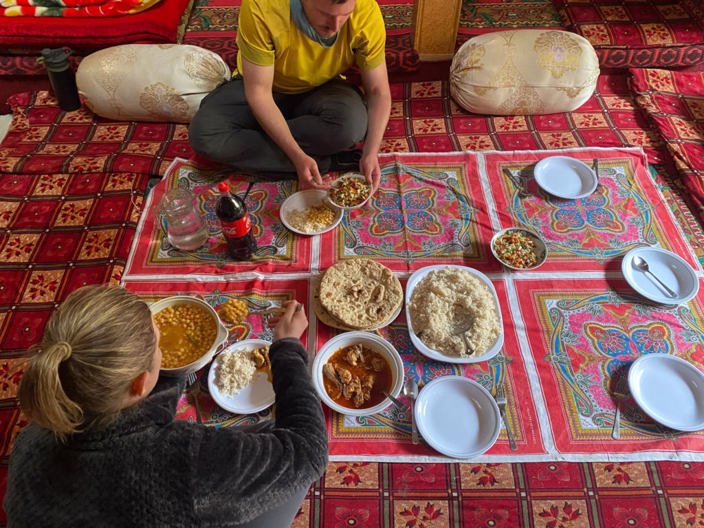 Photo of a foreign traveler being warmly greeted by a local Pakistani family or community in a mountain village.