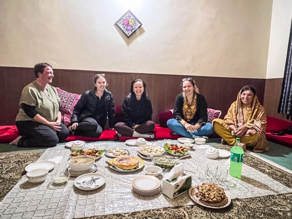 Photo of a foreign traveler being warmly greeted by a local Pakistani family or community in a mountain village.