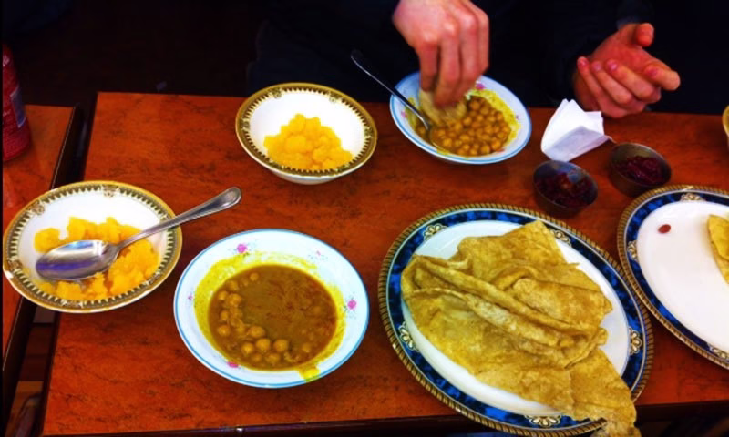 Lahori breakfast spread showing Halwa Puri with chickpea curry, halwa, lassi, and pickle
