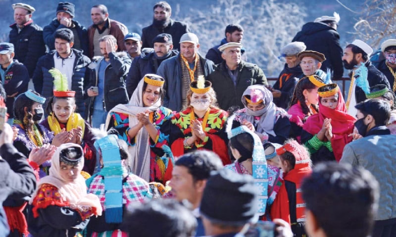Photograph of a Kalash ritual site or shrine showing the carved wooden posts and offerings that characterize Kalash sacred spaces