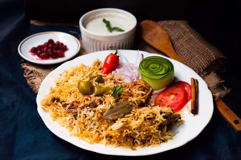 large serving of Pakistani Biryani on a platter with raita, salad, and pickles on the side